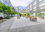 Thumbnail 17 of 18 - a courtyard with tables and chairs and trees and buildings in the background
