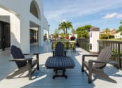 Thumbnail 21 of 33 - Pet-Friendly Apartments in Coconut Creek, FL – Waterview at Coconut Creek – sundeck with seating and palm trees in background