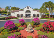 Thumbnail 32 of 33 - Pet-Friendly Apartments in Coconut Creek, FL – Waterview at Coconut Creek – outside leasing office with water fountain and lots of bushes with pink flowers
