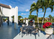 Thumbnail 19 of 33 - Apartments In Coconut Creek for Rent – Waterview at Coconut Creek – sundeck with table and chairs and palm trees in background