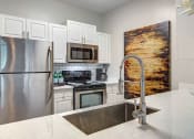 Thumbnail 1 of 25 - Alpharetta Apartments – The Ascent at Windward – Luxury kitchen with white cabinets, stainless-steel appliances and granite countertops