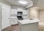 Thumbnail 1 of 27 - Woodstock, GA Apartments – Lea Woodstock – Luxury kitchen with quartz counter tops, white cabinets, stainless-steel appliances and hardwood floors