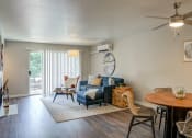 Thumbnail 3 of 31 - Mountain Park, OR, Apartments For Rent - MiLO - Living Room With Wood-Style Flooring, Area Rug, Sectional Couch, Side Table, Floor Lamp, Dining Area, Ceiling Fan, And Sliding Glass Door With Access to Balcony.