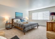 Thumbnail 8 of 31 - One-Bedroom Apartments in Mountain Park, OR - MiLO at Mountain Park - Bedroom with Carpeting, Large Window, Wooden Dresser, and 2 Nighstands with Lamps