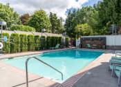 Thumbnail 22 of 31 - a swimming pool with lounge chairs and trees in the background