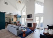 Thumbnail 15 of 31 - Mountain Park Apartments - MiLO at Mountain Park - Clubhouse with High Ceilings, Wood-Style Flooring, Area Rug, Couch, Armchairs, Coffee Station, and Fireplace