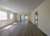 Thumbnail 14 of 33 - Coconut Creek Apartments – Waterview at Coconut Creek – empty living room with wood flooring and a door to a patio