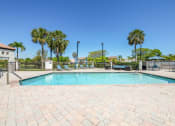Thumbnail 2 of 33 - Pet-Friendly Apartments in Coconut Creek, FL – Waterview at Coconut Creek – resort style swimming pool and sundeck with palm trees behind