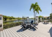 Thumbnail 22 of 33 - Coconut Creek Apartments – Waterview at Coconut Creek – deck has a palm tree and chairs on it