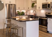 Thumbnail 8 of 67 - a kitchen with white cabinets and a large island with a black countertop