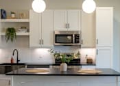 Thumbnail 9 of 67 - a kitchen with white cabinets and a black counter top