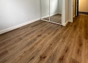 Thumbnail 15 of 20 - an empty living room with wood flooring and a mirrored closet at The Chase Apartment Homes, Oakland, CA 94606