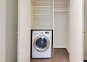 Thumbnail 10 of 15 - A white washing machine in a small laundry room.
