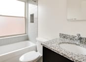 Thumbnail 3 of 15 - A white toilet sits next to a bathtub in a bathroom.