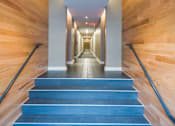 Thumbnail 12 of 15 - A long hallway with wooden walls and steps leading to the end.