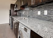 Thumbnail 7 of 15 - A modern kitchen with dark wood cabinets and a granite countertop.