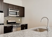 Thumbnail 1 of 15 - A kitchen with granite countertops and stainless steel appliances.