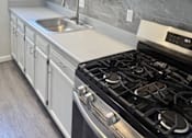 Thumbnail 3 of 17 - A kitchen with a black stove top oven and white cabinets.