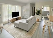 Thumbnail 2 of 17 - A living room with a white couch and a television.