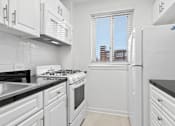 Thumbnail 23 of 59 - A white kitchen with black countertops and a window.