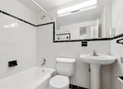 Thumbnail 22 of 59 - A white bathroom with a tub, toilet, and sink.