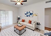 Thumbnail 26 of 63 - A living room with a white couch, a coffee table, and a ceiling fan.