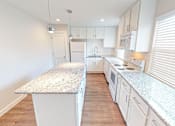 Thumbnail 8 of 27 - A kitchen with white cabinets and a granite countertop.