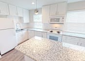 Thumbnail 6 of 27 - A kitchen with white cabinets and appliances.