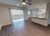 Thumbnail 14 of 27 - A spacious kitchen and living room with hardwood floors and a ceiling fan.
