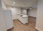 Thumbnail 16 of 27 - A white refrigerator stands in a kitchen with wooden floors and white walls.