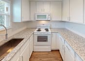 Thumbnail 15 of 42 - A white kitchen with a stove top oven and microwave.