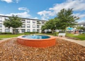 Thumbnail 7 of 26 - a round brick fountain sits in front of an apartment building