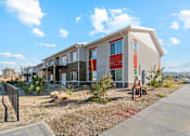 Thumbnail 1 of 36 - A modern building with a red door and windows is surrounded by a gravel area and a concrete walkway.