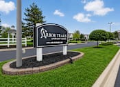 Thumbnail 1 of 37 - A sign for Arbor Trails Apartment Homes stands in a grassy area.