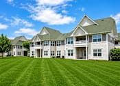 Thumbnail 4 of 22 - A large, well-maintained house with a green lawn in front.