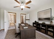 Thumbnail 30 of 30 - A room with a ceiling fan and a desk with a chair.