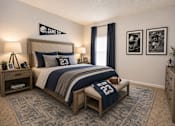 Thumbnail 16 of 18 - A bedroom with a bed, nightstands, and a football jersey on the bed.