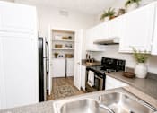Thumbnail 13 of 18 - A kitchen with white cabinets and a black stove top oven.