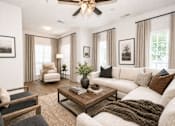 Thumbnail 10 of 18 - A living room with a white couch, a wooden coffee table, and a ceiling fan.