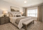 Thumbnail 17 of 18 - A bedroom with a large bed, a bench, and two lamps.