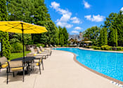 Thumbnail 4 of 18 - A pool with a yellow umbrella and chairs around it.