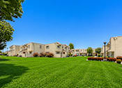 Thumbnail 2 of 12 - A row of houses with a green lawn in front.