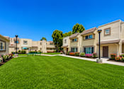Thumbnail 5 of 12 - A row of houses with a green lawn in front.