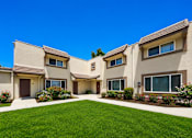 Thumbnail 4 of 12 - A row of houses with a green lawn in front.