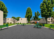 Thumbnail 11 of 12 - A street view of a residential area with houses, trees, and benches.
