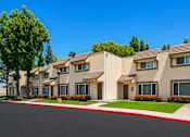 Thumbnail 6 of 12 - A row of houses with red trim and green bushes in front.