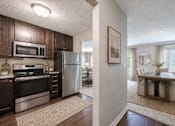 Thumbnail 4 of 9 - A kitchen with dark wood cabinets and stainless steel appliances.