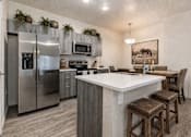 Thumbnail 22 of 33 - Modern kitchen with white countertops and island seating at Silver Ridge Apartments, Meridian, Idaho
