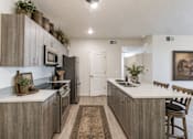 Thumbnail 21 of 33 - Modern kitchen with wood grain cabinetry and island at Silver Ridge Apartments, Meridian