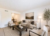 Thumbnail 15 of 21 - Living room with beige sofa and dark wood coffee table at Stonetree Apartments, East Point, 30344